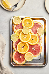 Naklejka na ściany i meble Top view of sliced ​​citrus on a tray. Orange, grapefruit, lemon and lime showcasing healthy food in a flat lay. Natural beauty, medical concept of cliced fruits.