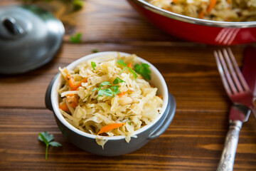 Braised cabbage with carrots, onions and herbs in a ceramic bowl