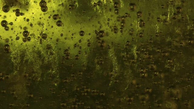 Macro slowmo Small bubbles rising in green viscous liquid with dark background 