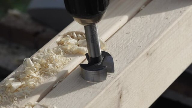 Milling the hole in wood. Worker with milling cutter in action. Countersink drill bit make sink in hole. Man uses drilling machine to make a hole on wooden plank