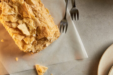 Piece of napoleon cake. Creamy vanilla slice dessert on a parchment paper. Layered baked pie. Copy space.