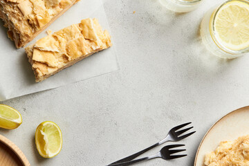 Piece of napoleon cake. Creamy vanilla slice dessert on a parchment paper. Layered baked pie with two glasses of water. Sweet food presentation. Copy space.