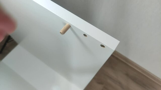 Furniture assembler connects pieces of furniture boards with wooden dowels