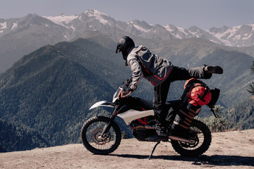 Male biker jumping on off-road motorcycle in moto trip in chic beautiful mountain gorge