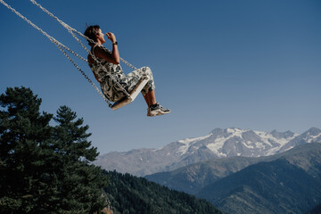 Naklejka na ściany i meble Dream and travel concept, Young beautiful female enjoying on swing flying in the sky over stunning mountain gorge