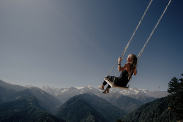 Dream and travel concept, Young beautiful woman enjoying  on swing flying in the sky over stunning mountain gorge - obrazy, fototapety, plakaty