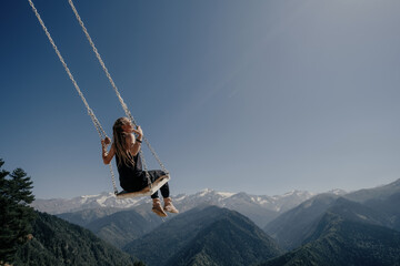 Dream and travel concept, Young beautiful female enjoying  on swing flying in the sky over amazing...