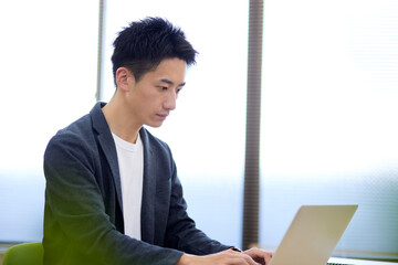 パソコンを操作雨する若い日本人のビジネスマン