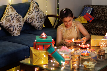 Close up of Young girl lighting Handcrafted Eco Friendly Clay Diya Deep Dia with ambient light bokeh for Hindu festival Laxmi poojan (Diwali)