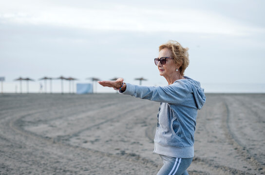 An Older Woman On The Beach Practicing Yoga. Concept Of Mental Health