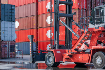 Crane lifting up container and unloading cargo into the import-export zone in yard.