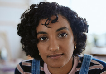 Face, eyes and portrait with a woman from India closeup inside with curly hair and a serious...
