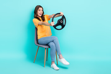 Full length photo of shiny impressed girl dressed yellow t-shirt sitting chair riding car looking...