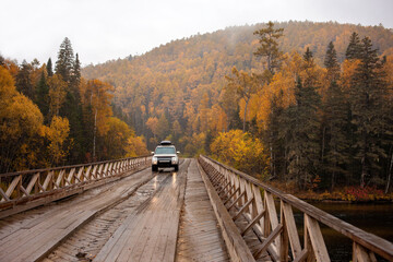 SUV on the wooden bridge over a mountain river