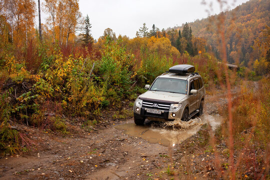 Khabarovsk, Russia- September 28, 2021: Mitsubishi Pajero crossing a puddle at a dirt forest road in autumn