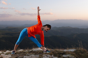 woman in bright clothes goes in for sports in the mountains doing a warm-up or assana from a pose...