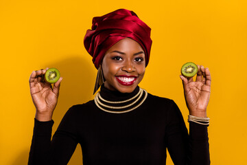 Photo of cheerful pretty person hold two halves kiwi wear nigeria outfit isolated on yellow color...