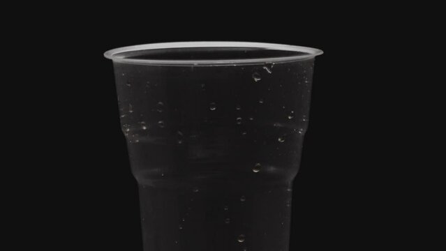 empty plastic water cup rotating against dark background
