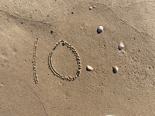 On the beach in the sand is carved the number 10