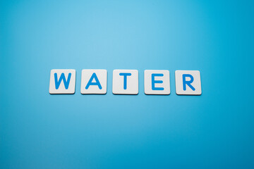 Word WATER on blue background,resources concept. Beautiful blue background. Close up
