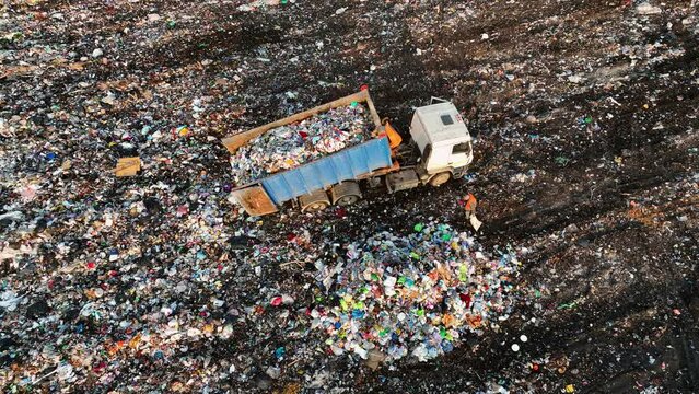 Garbage truck unloads rubbish. Landfill with solid household waste. Garbage dump with plastic and polyethylene. Solid waste disposal. Environmental pollution. Landfills Work with rubbish, garbage.