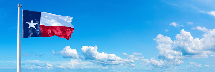 Texas - state of USA, flag waving on a blue sky in beautiful clouds - Horizontal banner
