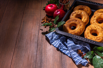 Traditional tasty ready to eat apple cider donuts. Homemade baked apple cinnamon donuts with apple pie crumble and spices, served on wooden table copy space