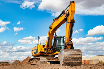 Powerful excavator at a construction site against a blue cloudy sky. Earthmoving equipment for...