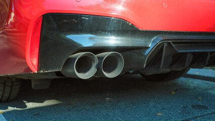 Close up of exhaust pipe of a red car. Twin exhaust pipes.