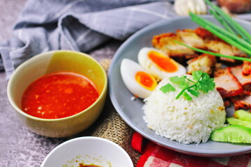 Thai dish '' Khao mu daeng '' or red sauce pork stew with rice and spring onions served in a gray plate on the black table in the restuarant