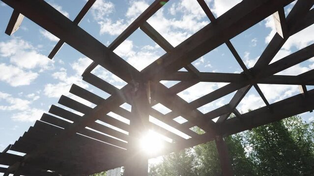 Wooden pergola in a city recreation park with a lake in the residential area