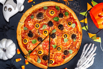Halloween creative food. funny monster pizza decorated with creepy eyes, on black table background...