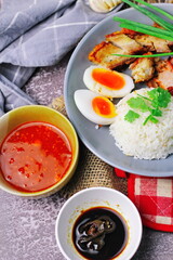 Thai dish '' Khao mu daeng '' or red sauce pork stew with rice and spring onions served in a gray...