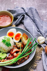 Thai dish '' Khao mu daeng '' or red sauce pork stew with rice and spring onions served in a gray plate on the black table in the restuarant