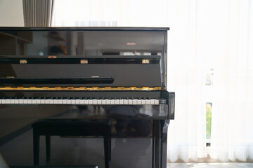 Black piano classic in home living room with bright white curtain background