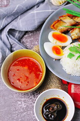 Thai dish '' Khao mu daeng '' or red sauce pork stew with rice and spring onions served in a gray plate on the black table in the restuarant