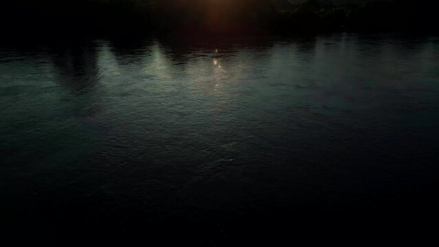 4K Cinematic nature aerial footage of a drone flying over the Mekong River on the border between Thailand and Laos facing the mountains during a beautiful sunset.