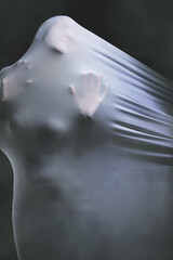 Psychology, fabric and horror with the hands of a woman trapped in textile in studio on a dark...