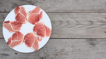 Raw Pork Slice in White Round Plate on old Wooden Table. Slide raw meat on the table. Top view
