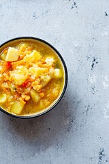 Soup with red lentils and vegetables in a bowl on a blue background.Traditional dish of Turkish or Arabic cuisine, vegan healthy food.