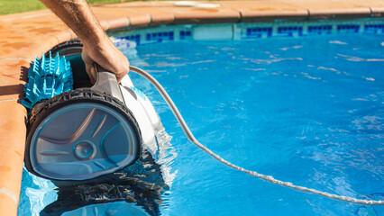 Man pulling out the robotic pool cleaner with his hand. Pool robot for maintenance of the floor and...