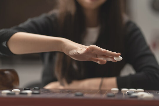 close-up woman hand holding the stone on GO board game