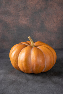 Beautiful bright pumpkin on brown background. Halloween minimal concept, Vertical image