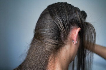 Naklejka premium Gray hairs on the head of a young girl. Long gray hair. The initial stage of gray hair. The problem of gray hair in women.