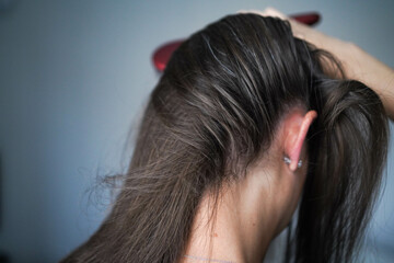 A woman combs her hair. Gray hairs on the head of a young girl. Long gray hair. The initial stage...