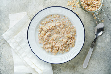 Oatmeal. Bowl of oatmeal porridge with strawberry, almond and milk on vintage light grey teal table. Top view in flat lay style. Natural ingredients. Hot and healthy breakfast and diet food.