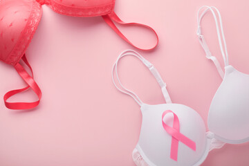 Obraz na płótnie Canvas Breast Cancer Awareness Ribbon. White and red bra with pink ribbon tape lying on female bra on backgrounds. Breast cancer awareness and October Pink day, world cancer day. Top view. Mock up.