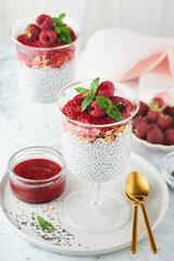Chia pudding. Healthy vanilla chia pudding in glass with fresh raspberries and mint on white background. Vegan healthy breakfast.