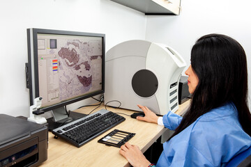 Young female scientist scanning microscope slides with tissue samples for pathology studies. Cancer diagnosis concept. Medical technology concept. - obrazy, fototapety, plakaty