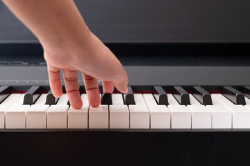 Closeup to woman left hand on the piano key. Practicing music instrument.